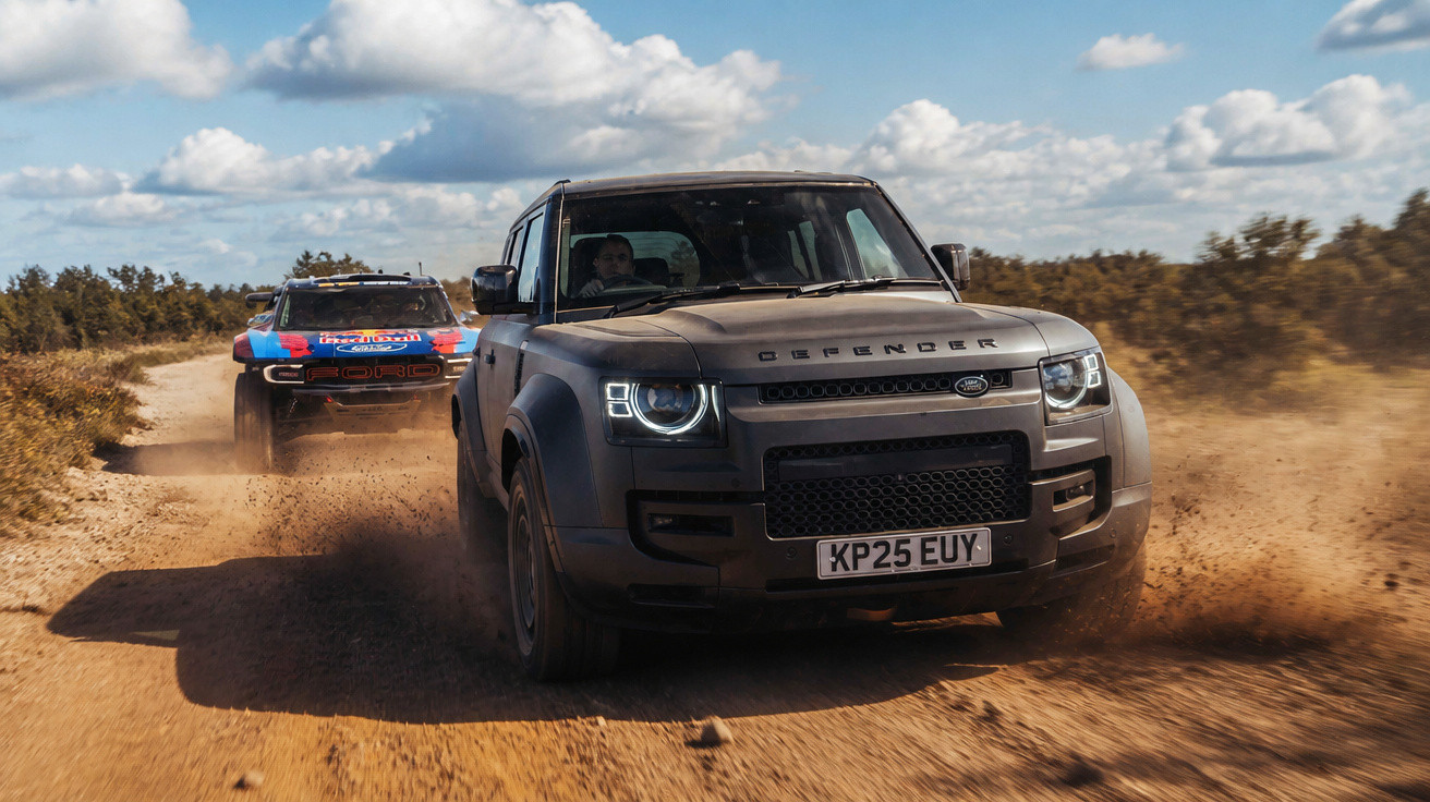 Two off-road vehicles kicking up dust on a dirt trail under a partly cloudy sky.